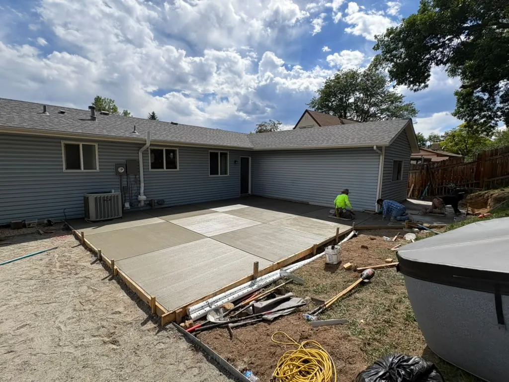 Crew finishing a large new backyard concrete patio in the Denver area