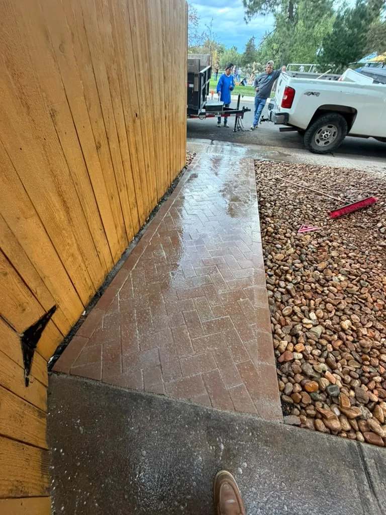 Red herringbone paver walkway next to river rock landscaping