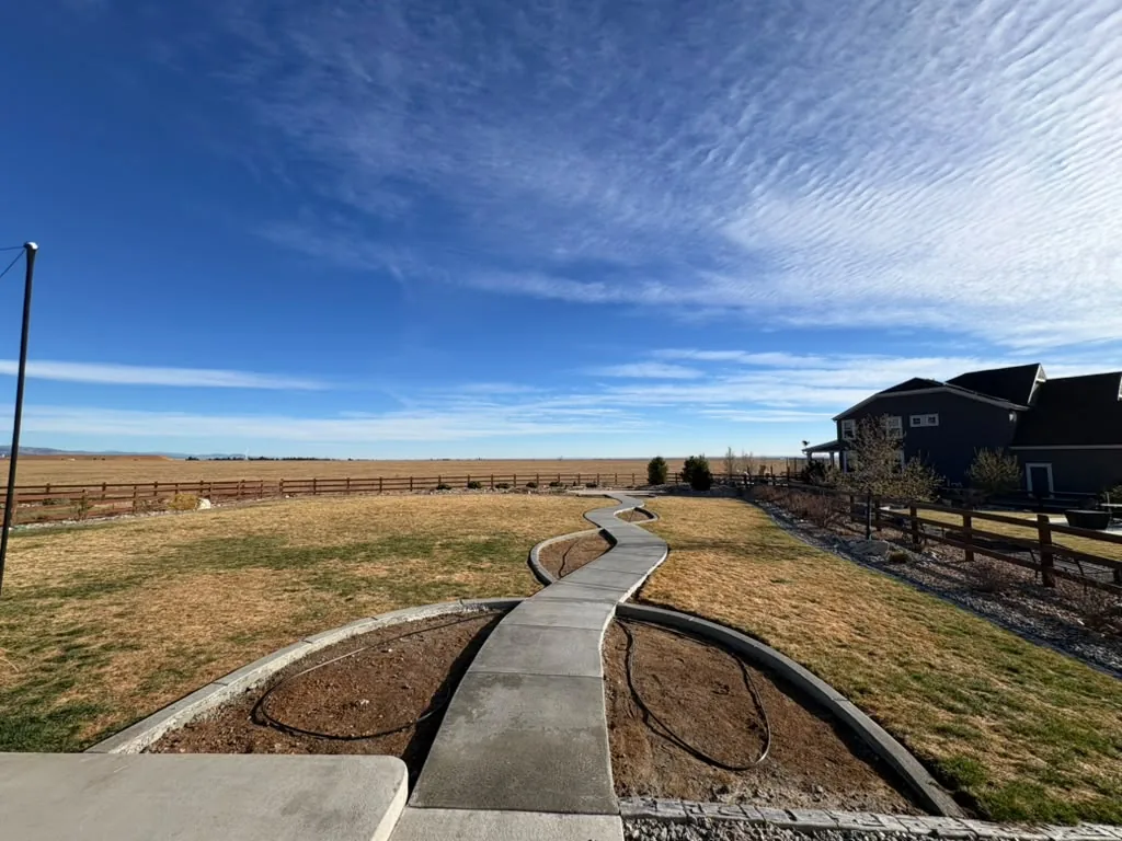 Serpentine concrete path and flower beds under a Colorado sky